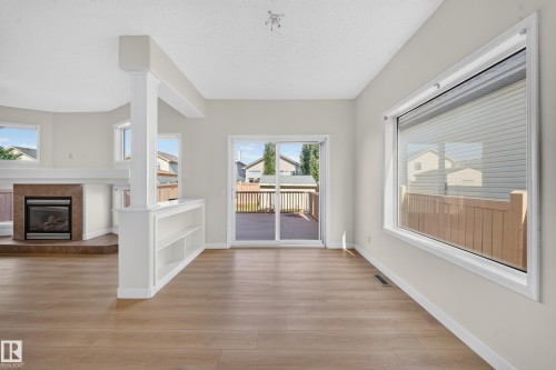 Wood-finish flooring, built-in shelving, fireplace with mantel, and sliding glass door leading to an outdoor deck - 7836 7 Ave Sw Sw, Edmonton, AB 