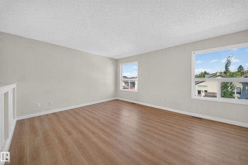 Light-toned walls, wood-finish flooring, two windows, and white trim - 7836 7 Ave Sw Sw, Edmonton, AB 