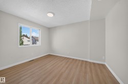 Bright room featuring wood-finish flooring, a large window, a flush-mount ceiling light, and light-toned walls - 