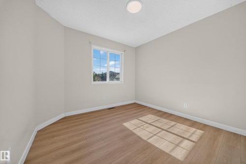 Neutral-toned walls, wood-finish flooring, white trim, and a flush-mount ceiling light - 7836 7 Ave Sw Sw, Edmonton, AB 