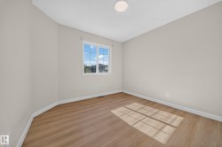 Neutral-toned walls, wood-finish flooring, white trim, and a flush-mount ceiling light - 