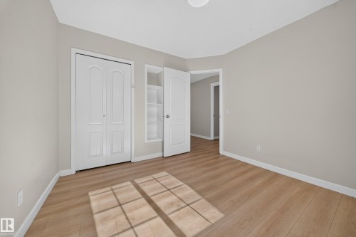 Light wood-finish flooring, neutral wall tones, white trim, and a ceiling-mounted light fixture - 7836 7 Ave Sw Sw, Edmonton, AB 