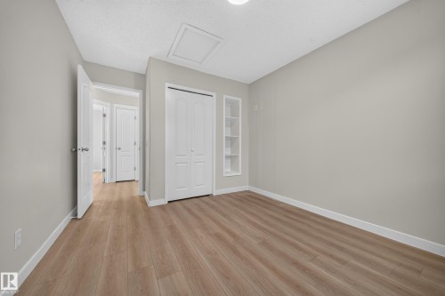 Wood-finish flooring, built-in shelving, white bi-fold closet doors, and recessed lighting - 7836 7 Ave Sw Sw, Edmonton, AB 