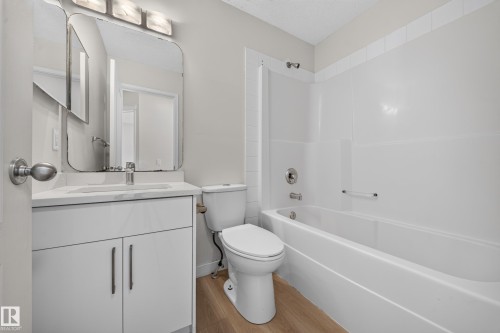 White vanity with a rectangular undermount sink, a chrome faucet, and a large wall-mounted mirror - 7836 7 Ave Sw Sw, Edmonton, AB 
