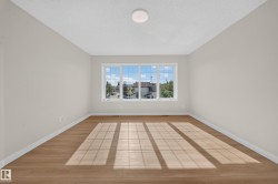 Expansive room featuring a large multi-pane window, wood-finish flooring, and a flush-mount ceiling light fixture - 