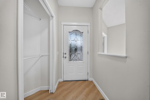 Wood-finish flooring, white entry door with decorative glass, built-in shelving, and a wall cutout - 7836 7 Ave Sw Sw, Edmonton, AB 