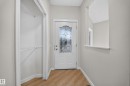 Wood-finish flooring, white entry door with decorative glass, built-in shelving, and a wall cutout - 7836 7 Ave Sw Sw, Edmonton, AB 