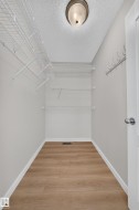 Recessed ceiling light, white wire shelving, wall-mounted coat hooks, wood-finish flooring, white trim - 