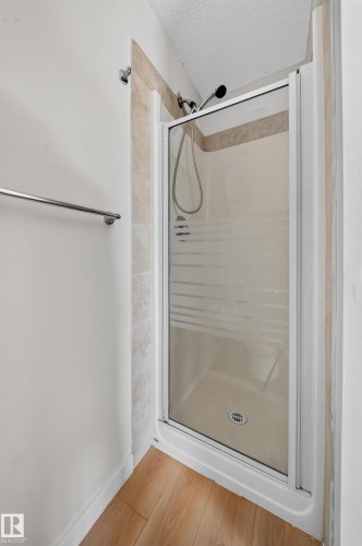 Enclosed shower stall with a frosted glass door, tiled surround, and a chrome shower head - 7836 7 Ave Sw Sw, Edmonton, AB 