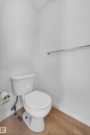 White toilet with wood-finish flooring and a chrome towel bar - 