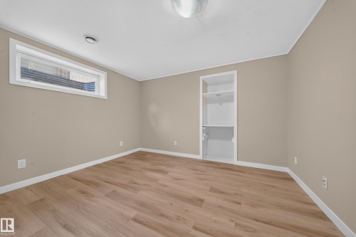Wood-finish flooring, neutral wall color, built-in shelving, white trim, and a high horizontal window - 7836 7 Ave Sw Sw, Edmonton, AB 