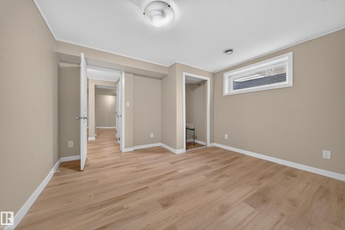 Wood-finish flooring, neutral-toned walls, and a window with white trim - 7836 7 Ave Sw Sw, Edmonton, AB 