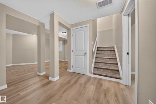 Expansive room featuring wood-finish flooring, neutral-toned walls, and white trim - 7836 7 Ave Sw Sw, Edmonton, AB 