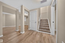 Expansive room featuring wood-finish flooring, neutral-toned walls, and white trim - 