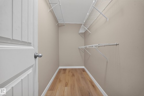 Walk-in closet featuring wood-finish flooring, neutral wall color, and white wire shelving - 7836 7 Ave Sw Sw, Edmonton, AB 