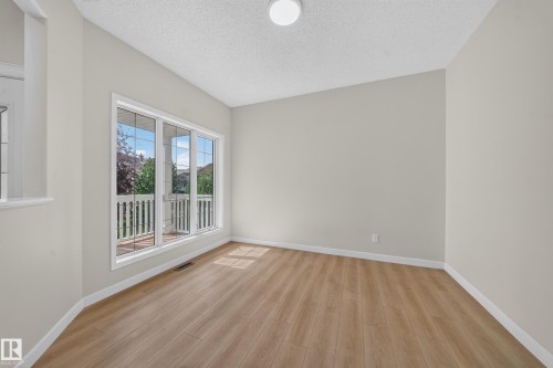 Expansive window with white trim, wood-finish flooring, light neutral wall paint, and overhead lighting - 7836 7 Ave Sw Sw, Edmonton, AB 