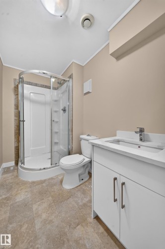 Walk-in shower with clear enclosure, white vanity with integrated sink, modern chrome faucet, and rectangular floor tiling - 7836 7 Ave Sw Sw, Edmonton, AB 