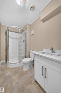 Walk-in shower with clear enclosure, white vanity with integrated sink, modern chrome faucet, and rectangular floor tiling - 