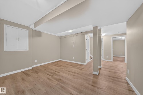 Wood-finish flooring throughout, light neutral wall color, white crown molding, and white trim - 7836 7 Ave Sw Sw, Edmonton, AB 