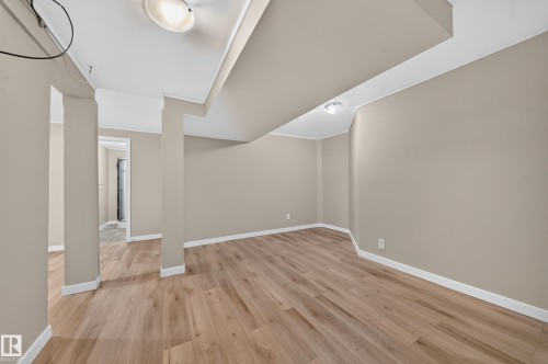 Spacious room featuring wood-finish flooring and neutral wall tones - 7836 7 Ave Sw Sw, Edmonton, AB 