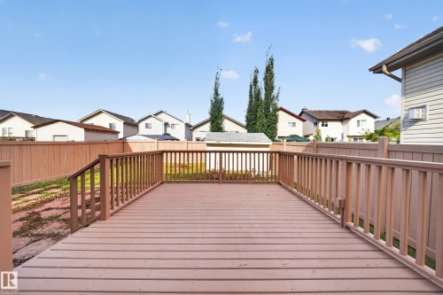 Expansive wooden deck with coordinating railings, leading to a fenced yard - 7836 7 Ave Sw Sw, Edmonton, AB 