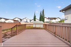 Expansive wooden deck with coordinating railings, leading to a fenced yard - 