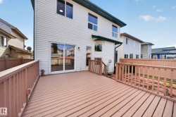 Expansive wood-finish deck with railing, sliding glass door access, and exterior wall lighting - 