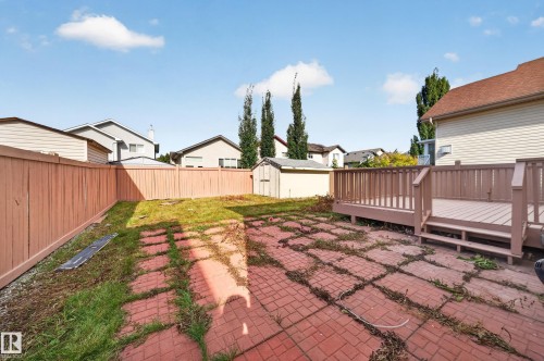 Expansive backyard featuring a wood deck, red brick-patterned patio, and a wood fence - 7836 7 Ave Sw Sw, Edmonton, AB 