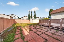 Expansive backyard featuring a wood deck, red brick-patterned patio, and a wood fence - 
