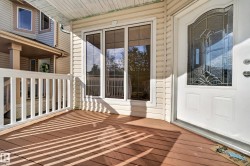 Front porch with wood-finish decking, white railings, and vinyl siding - 