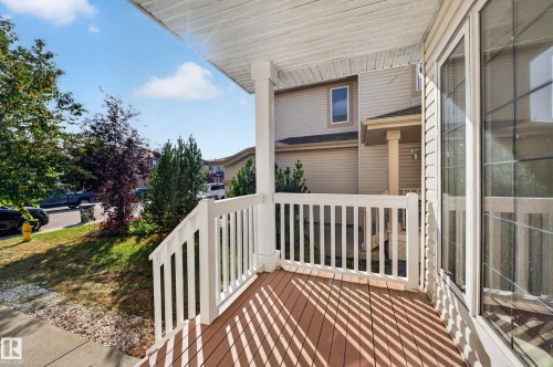 Front porch featuring composite decking, white railing, and a columned entrance - 7836 7 Ave Sw Sw, Edmonton, AB 
