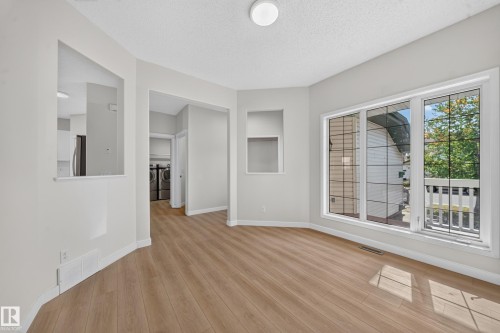 Wood-finish flooring, white trim, recessed wall niche, large window with muntins, and ceiling-mounted light fixture - 7836 7 Ave Sw Sw, Edmonton, AB 