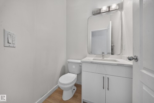White vanity with a rectangular sink, wall-mounted mirror, and overhead light fixture - 7836 7 Ave Sw Sw, Edmonton, AB 