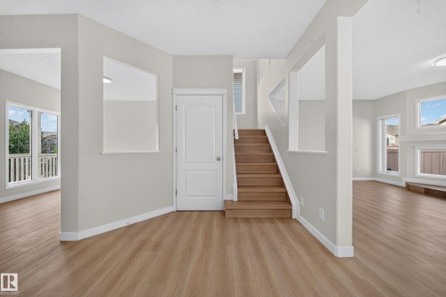 Light wood-finish flooring, staircase with wood treads, abundant natural light, neutral wall colors, and built-in architectural shelving - 7836 7 Ave Sw Sw, Edmonton, AB 