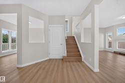 Light wood-finish flooring, staircase with wood treads, abundant natural light, neutral wall colors, and built-in architectural shelving - 