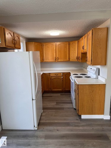 U-shaped kitchen featuring wood cabinetry, white countertops, and wood-finish flooring - 9G Clareview Village Nw, Edmonton, AB 