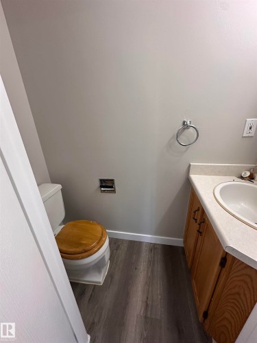 Wood-finish flooring with white baseboards, light-toned walls, and a vanity with a drop-in sink - 9G Clareview Village Nw, Edmonton, AB 
