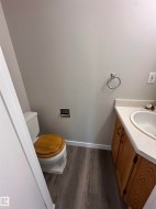 Wood-finish flooring with white baseboards, light-toned walls, and a vanity with a drop-in sink - 
