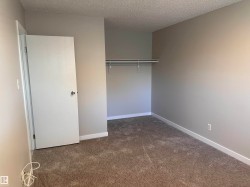 Neutral-toned walls, textured ceiling, brown carpet flooring, and a built-in closet rod - 