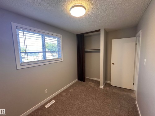 Neutral wall paint with textured carpeting, a single window with blinds, and an open closet space - 9G Clareview Village Nw, Edmonton, AB 