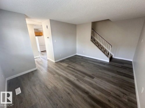 Wood-finish flooring throughout, light gray wall paint, and a staircase with white railings - 9G Clareview Village Nw, Edmonton, AB 