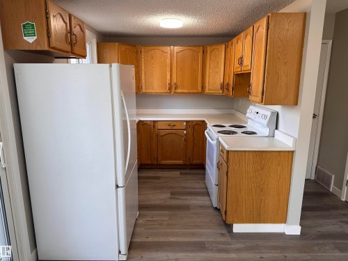 Wood-finish flooring, white countertops, built-in cabinetry, and a built-in range - 9G Clareview Village Nw, Edmonton, AB 