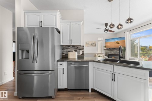 Stainless steel appliances, white cabinetry with dark hardware, stone-look countertops, subway tile backsplash, and wood-finish flooring - #5 4900 62 St, Beaumont, AB 