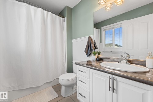 White vanity with integrated sink and chrome faucet, dark countertop, and decorative wall paneling - #5 4900 62 St, Beaumont, AB 