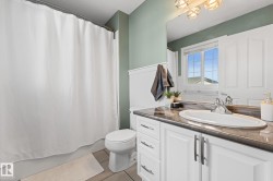 White vanity with integrated sink and chrome faucet, dark countertop, and decorative wall paneling - 