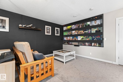 Built-in media screen wall, recessed ceiling lighting, light gray carpeting, and a white paneled door - #5 4900 62 St, Beaumont, AB 