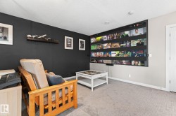 Built-in media screen wall, recessed ceiling lighting, light gray carpeting, and a white paneled door - 
