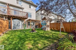 Expansive backyard featuring a manicured lawn, wood fencing, a ground-level patio with a pergola, and a raised wood-finish deck - 