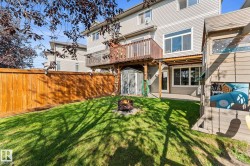 Expansive backyard featuring a manicured lawn, a wooden privacy fence, and a multi-level wood deck - 