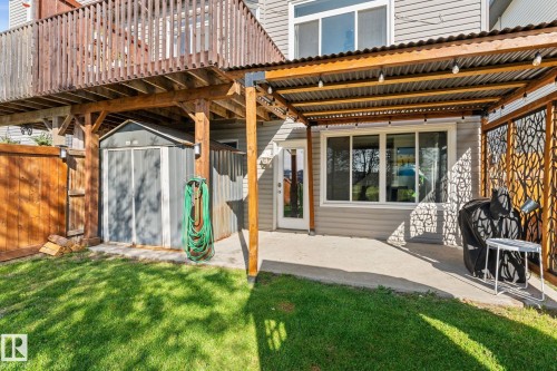 Covered concrete patio with decorative privacy screen, featuring a wood-framed overhead deck and a built-in storage shed - #5 4900 62 St, Beaumont, AB 